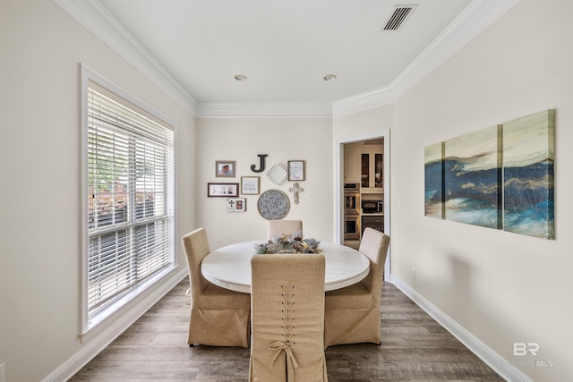 dining area with ornamental molding and dark hardwood / wood-style floors