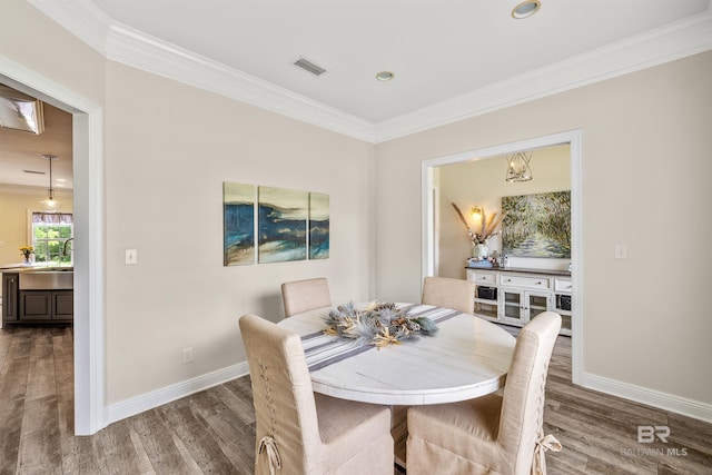 dining area with dark wood-type flooring, sink, and ornamental molding