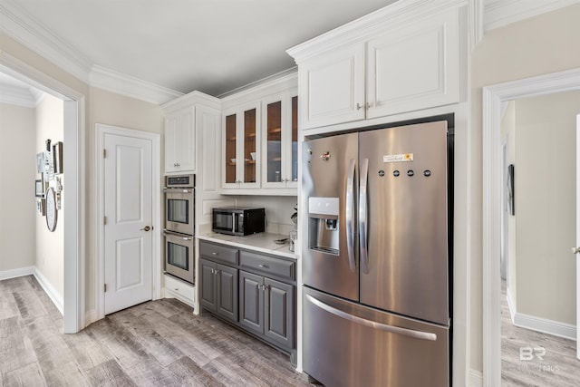 kitchen with appliances with stainless steel finishes, ornamental molding, gray cabinets, white cabinetry, and light wood-type flooring