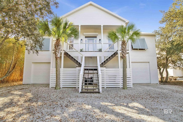 coastal inspired home with covered porch, driveway, and stairs