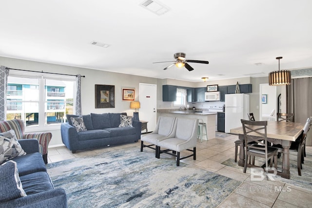 living room featuring light tile patterned floors, ceiling fan, and a wealth of natural light