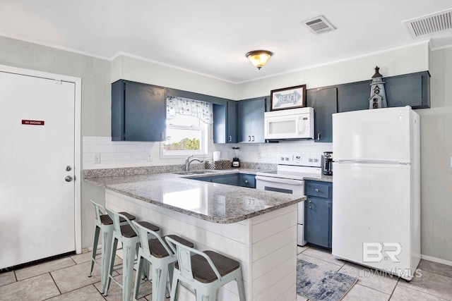 kitchen with white appliances, a breakfast bar, decorative backsplash, light tile patterned flooring, and sink
