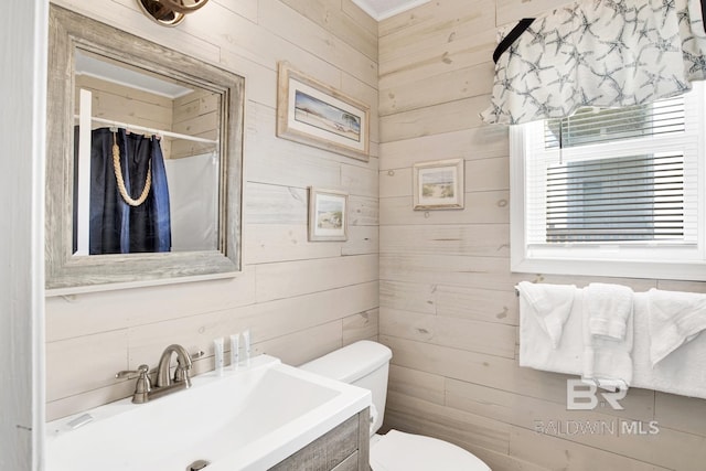 bathroom with toilet, a shower with shower curtain, vanity, and wooden walls