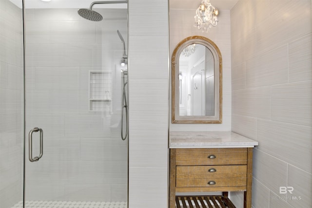 453 Dune Dr Unit 101, Gulf Shores, AL 36542 - bathroom with a stall shower, vanity, tile walls, and a notable chandelier