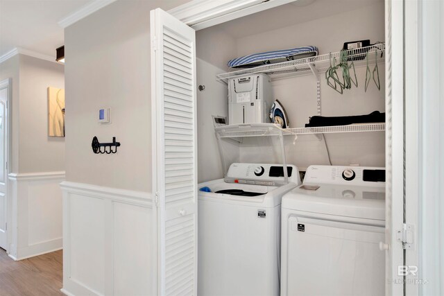 clothes washing area featuring crown molding, light hardwood / wood-style flooring, water heater, and separate washer and dryer