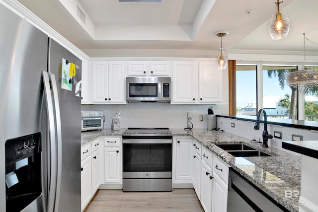 kitchen featuring pendant lighting, white cabinetry, stainless steel appliances, and a tray ceiling