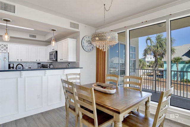 453 Dune Dr Unit 101, Gulf Shores, AL 36542 - dining room featuring a notable chandelier, light wood-style flooring, and visible vents