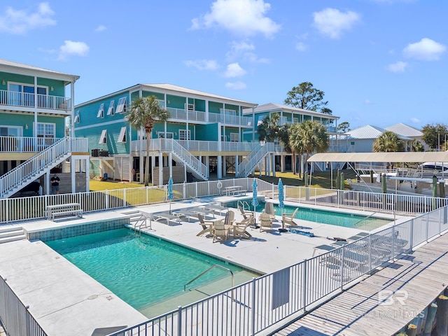 pool with a patio, stairway, and fence