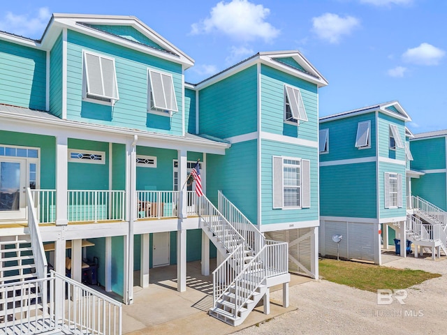 view of front of home with driveway, stairway, a porch, and a carport