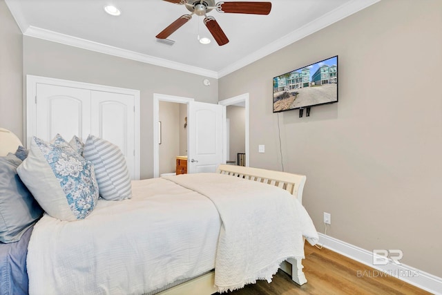 bedroom featuring ornamental molding, wood finished floors, visible vents, and baseboards