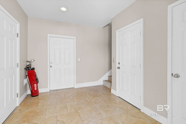 foyer entrance featuring stairway and baseboards