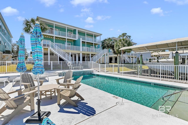 community pool featuring stairs, a patio area, and fence