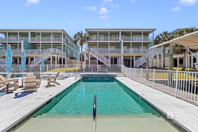 pool featuring a patio area, fence, and stairway