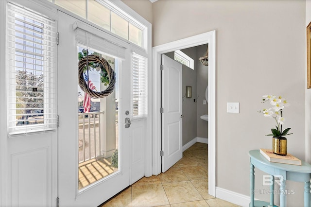 foyer with plenty of natural light, baseboards, and light tile patterned floors