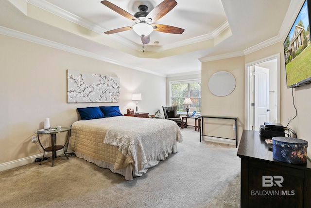 carpeted bedroom with ornamental molding, ceiling fan, and a tray ceiling