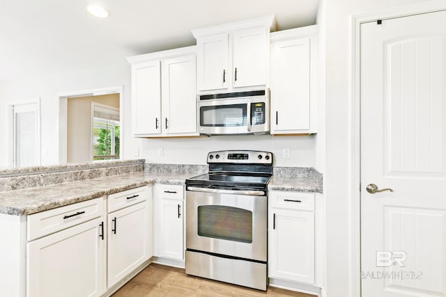 kitchen featuring white cabinetry, appliances with stainless steel finishes, light hardwood / wood-style floors, and light stone counters