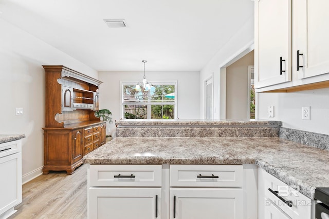 kitchen with pendant lighting, light stone counters, light hardwood / wood-style floors, and white cabinets