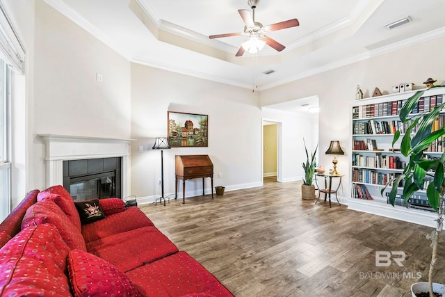 interior space featuring hardwood / wood-style flooring, ceiling fan, a tiled fireplace, and crown molding