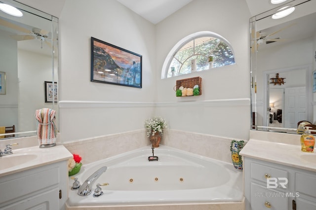 bathroom with vanity, tiled tub, and ceiling fan