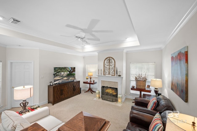 living room featuring a tiled fireplace, crown molding, light colored carpet, and a tray ceiling