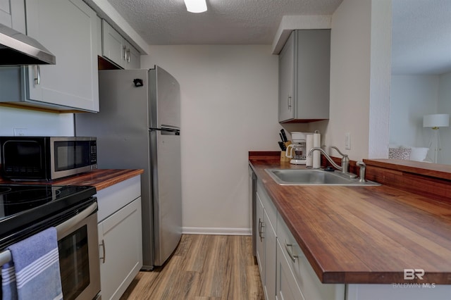 106 Golf Ter Unit 106, Daphne, AL 36526 - kitchen featuring wood counters, range hood, a sink, stainless steel appliances, and light wood finished floors