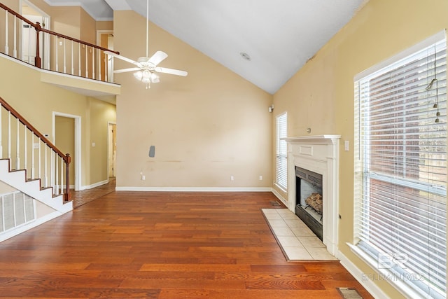 unfurnished living room featuring baseboards, visible vents, a tile fireplace, wood finished floors, and stairs