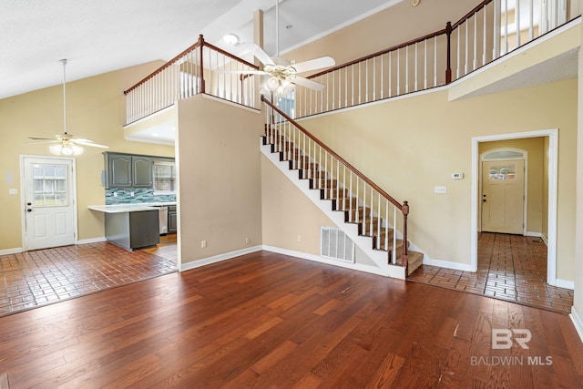 unfurnished living room featuring a ceiling fan, baseboards, stairway, and hardwood / wood-style floors