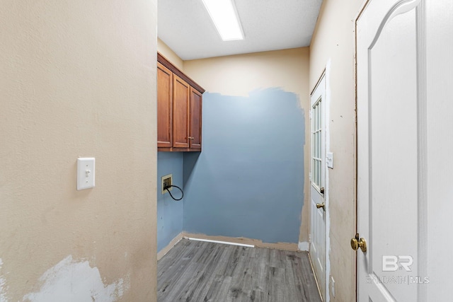 clothes washing area featuring hookup for a washing machine, cabinet space, and wood finished floors