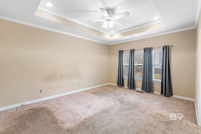 carpeted spare room featuring recessed lighting, a ceiling fan, baseboards, ornamental molding, and a tray ceiling