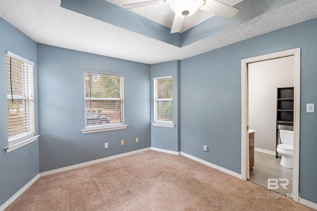 unfurnished bedroom featuring carpet, multiple windows, baseboards, and a textured ceiling