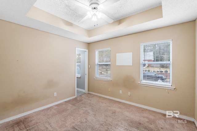 empty room featuring ceiling fan, a textured ceiling, a raised ceiling, and carpet flooring