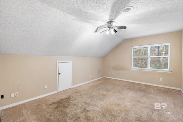 additional living space with carpet floors, ceiling fan, vaulted ceiling, and a textured ceiling