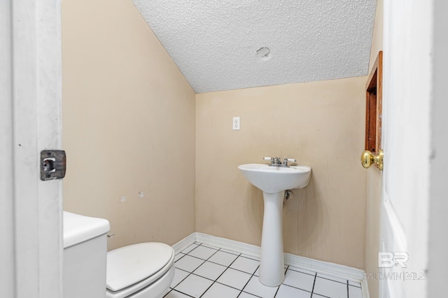 half bathroom featuring lofted ceiling, toilet, a textured ceiling, tile patterned flooring, and baseboards