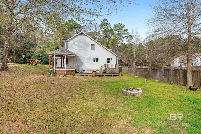 rear view of house featuring a fire pit, a yard, crawl space, and fence