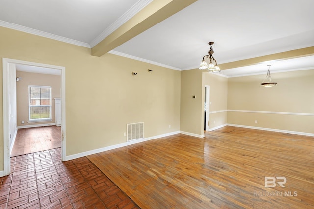 empty room featuring ornamental molding, visible vents, baseboards, and wood finished floors