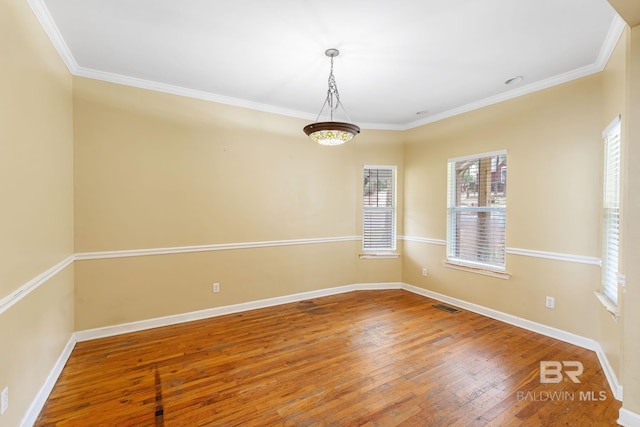 spare room with hardwood / wood-style flooring, baseboards, visible vents, and ornamental molding