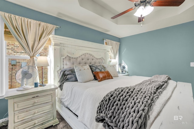 bedroom featuring carpet flooring, multiple windows, ceiling fan, and a tray ceiling