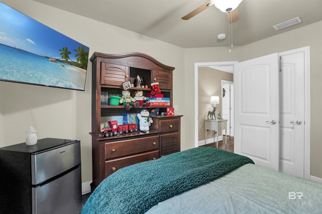 bedroom with ceiling fan, stainless steel fridge, and dark hardwood / wood-style flooring