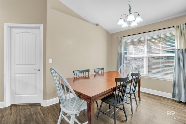 dining space with hardwood / wood-style floors, vaulted ceiling, and an inviting chandelier