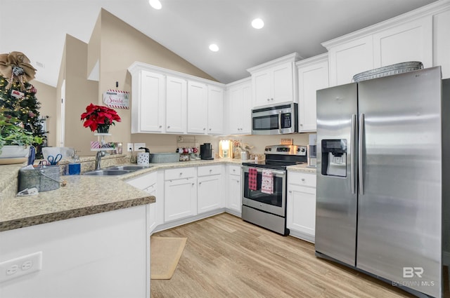 kitchen with light wood-type flooring, stainless steel appliances, sink, white cabinets, and lofted ceiling