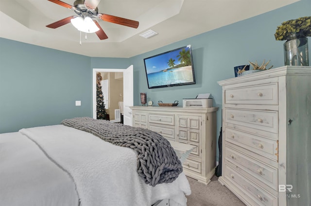 bedroom featuring a raised ceiling, ceiling fan, and light colored carpet