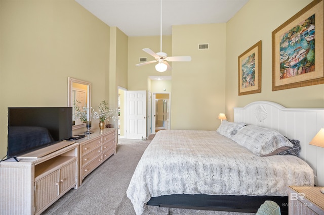 carpeted bedroom with a high ceiling, ceiling fan, and ensuite bath