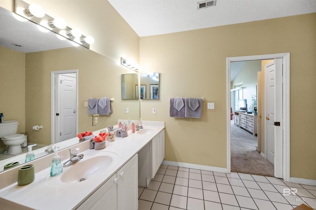 bathroom with tile patterned flooring, vanity, toilet, and a textured ceiling