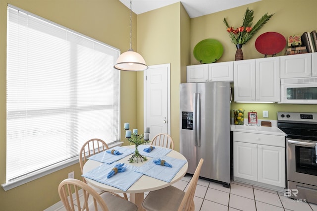 kitchen featuring white cabinets, appliances with stainless steel finishes, light tile patterned floors, and pendant lighting