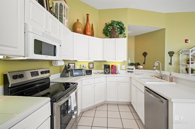 kitchen featuring sink, kitchen peninsula, appliances with stainless steel finishes, light tile patterned floors, and white cabinets