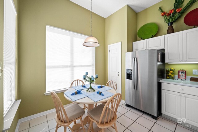 kitchen with white cabinetry, light tile patterned floors, decorative light fixtures, and stainless steel fridge with ice dispenser