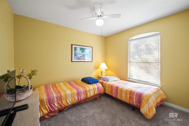 carpeted bedroom with ceiling fan and a textured ceiling