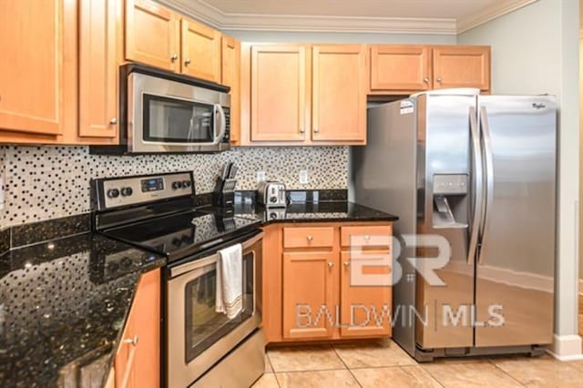 kitchen with light tile patterned floors, dark stone countertops, ornamental molding, appliances with stainless steel finishes, and decorative backsplash