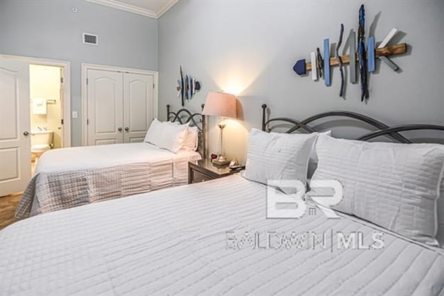 bedroom featuring ornamental molding, ensuite bathroom, and a closet