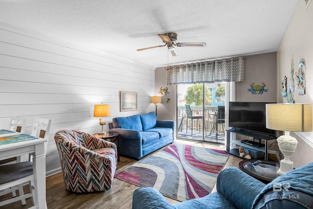 living room featuring ceiling fan, wood-type flooring, and a textured ceiling